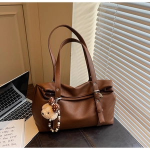 Detail of dark brown textured leather tote with silver studs and cute bear pendant
