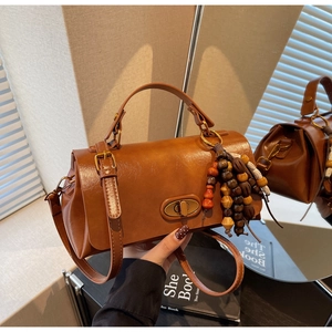 Close-up of vintage brown crossbody bag with gold twist lock and beaded tassel charm