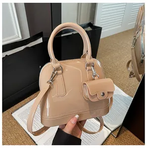 Macro shot of glossy beige shell bag with matching mini charm and detachable strap