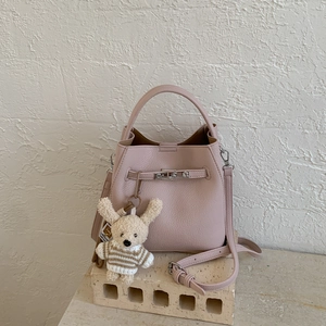 Detail of pink bucket bag with lychee grain leather, silver hardware and bear charm