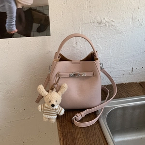 Macro shot of pink lychee leather texture and bear charm on the bucket handbag