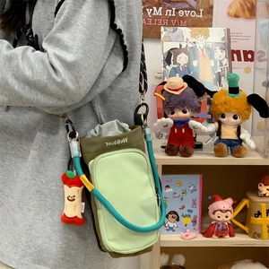 Detail of army green canvas crossbody bag with drawstring closure and red apple pendant