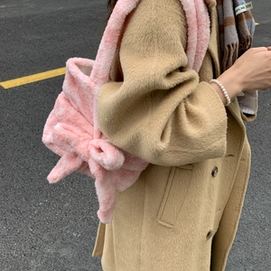 Detail of pink plush shoulder bag featuring a large decorative bow and soft faux fur texture