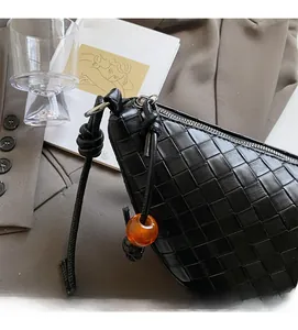 Détail d'un sac à bandoulière en cuir tressé noir avec perle orange et nœud