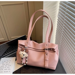 Pink lychee texture leather tote bag detail with plush bear charm and bow accessory