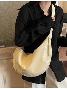 Creamy crescent moon hobo bag in glossy leather worn by model for casual commute