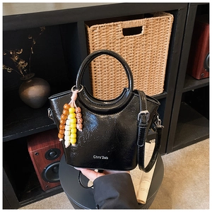 Glossy black bucket bag with circular handle, colorful beads and removable strap