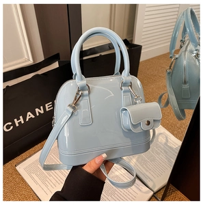 Detail of light blue glossy jelly shell bag with matching mini charm and top handle