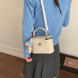 Detail of cream leather box bag with silver twist lock and cute bear charm pendant