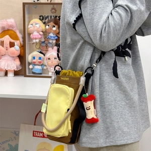 Brown crossbody bag with yellow accents, adjustable strap and red apple charm detail