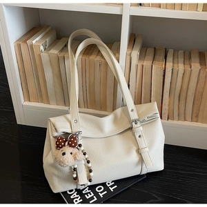 Detail of off-white lychee texture tote bag with cute plush bear charm and silver buckle