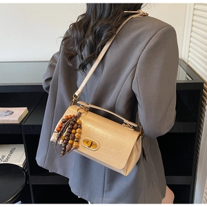 Detail of beige faux leather crossbody bag with gold twist lock and colorful wooden beads