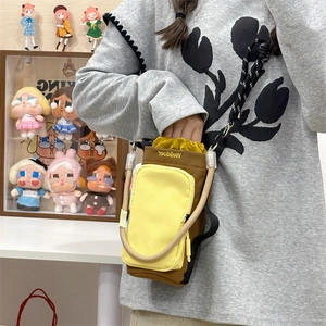 Detail of canvas crossbody bag showing brown fabric and yellow front zipper pocket