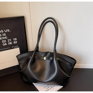 Detailed close-up of a black tote bag featuring lychee texture and golden buckle