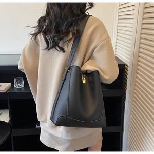Detailaufnahme der schwarzen Beuteltasche aus Leder mit Metallschloss und breitem Gurt
