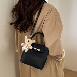 Close-up of black textured bucket bag with silver metal lock and cute bear charm