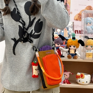 Detail of crossbody bag with orange pocket, Wellbear embroidery and plush apple charm