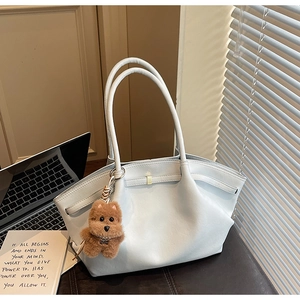 Close-up of light blue leather tote bag with subtle side pleats and plush puppy charm
