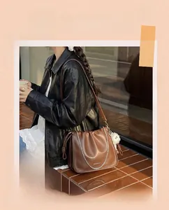Detailed close-up of brown bucket bag with metal chain and white faux fur pompom