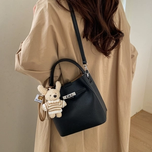 Detail of black lychee grain leather bucket bag with silver twist lock and bear charm
