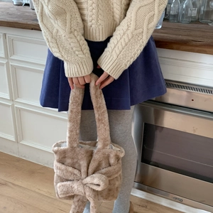 Light camel plush shoulder bag featuring a large decorative bow in a kitchen setting
