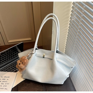 Detail of light blue tote bag with dual straps and cute brown teddy bear charm accessory