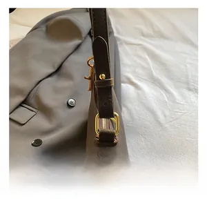 Detailed close-up of premium dark brown crescent bag with gold-tone buckle and textured leather