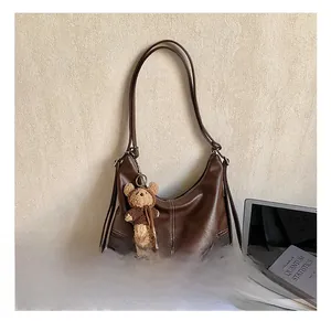 Detail view of dark brown faux leather tote bag with contrast stitching and bear charm