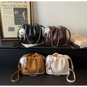 Detail of four pleated bucket bags in black, brown, tan, and beige with chain straps