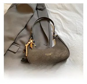 Detail of dark grey retro hobo bag with gold lettering and wooden bead charm accessory