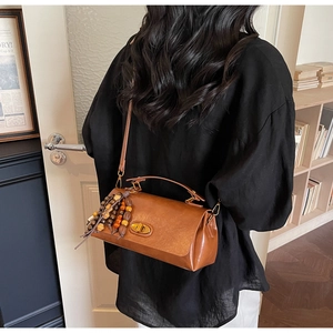 Detail of vintage brown crossbody bag with gold twist lock and colorful bead tassel