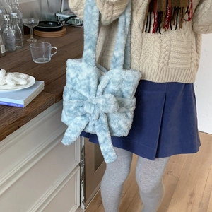 Detail of light blue fuzzy tote bag with oversized bow and soft plush texture