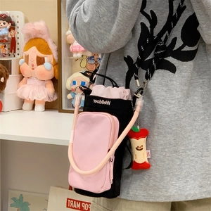 Close-up of black and pink crossbody phone bag with woven strap and apple charm