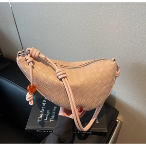 Detailed view of pink woven leather texture on a crescent shoulder bag with knot strap