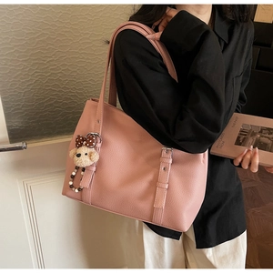 Close-up of pink lychee texture leather tote bag with a cute plush dog charm
