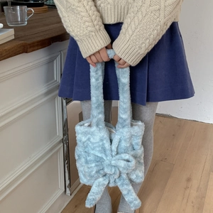 Close-up of a light blue plush handbag featuring a large soft bow and fuzzy texture