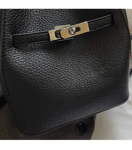 Detail of black lychee grain leather handbag with silver metallic twist lock and strap
