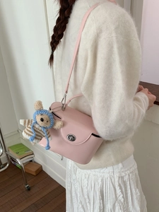 Pink faux leather crossbody box bag with cute knit bear charm on a white sweater