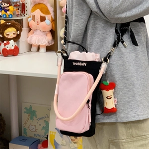 Crossbody bottle bag featuring pink drawstring, woven strap and cute apple charm detail