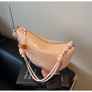 Close-up of pink woven crescent bag featuring a knotted strap and orange bead detail
