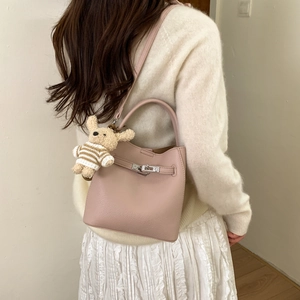 Detail of pink lychee leather bucket bag with metal buckle and plush rabbit charm