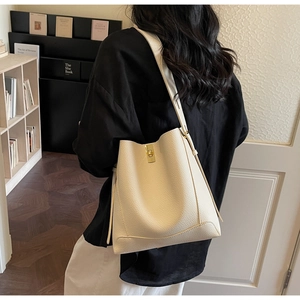 Detailaufnahme der cremefarbenen Leder-Beuteltasche mit goldenem Drehverschluss und Nähten
