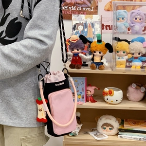 Pink and black nylon crossbody bag with adjustable strap and apple charm in shop background