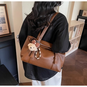 Detail of a brown lychee pattern tote bag with a cute plush bear charm decoration