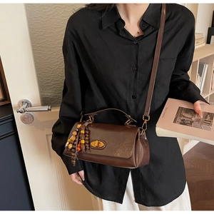 Detail of vintage brown leather handbag with gold twist lock and beaded tassel charm