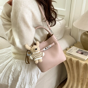 Detail of pink lychee grain leather bucket bag with silver lock and bear pendant