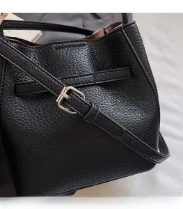 Detail of adjustable shoulder strap and silver buckle on black pebbled leather bucket bag
