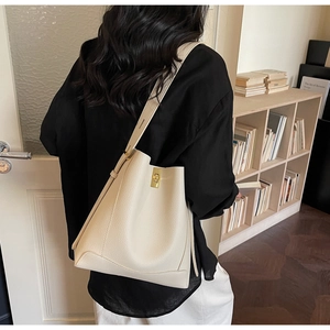Detailansicht der cremefarbenen Beuteltasche mit Lychee-Leder und goldenem Drehverschluss