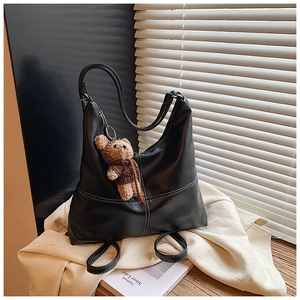 Detail of black matte leather tote with white contrast stitching and plush bear charm