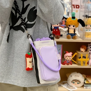 Detail of purple crossbody water bottle bag with adjustable strap and apple plush charm